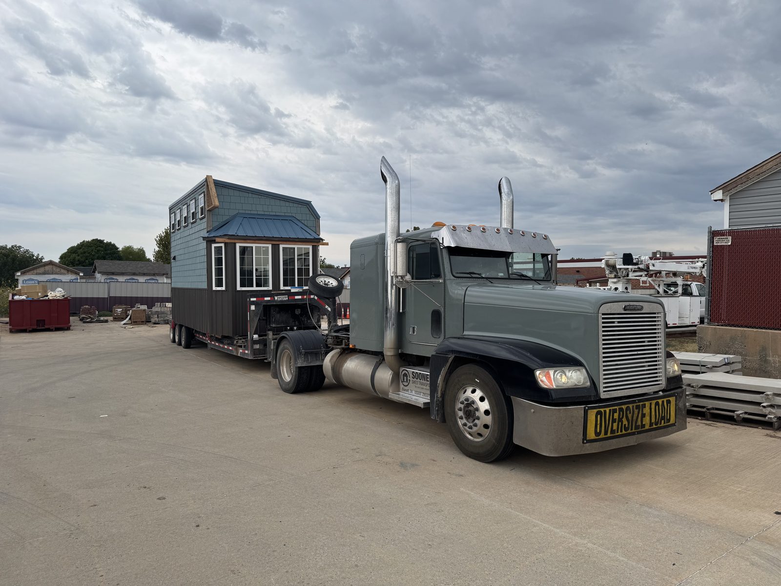 Two-story blue tiny house being hauled